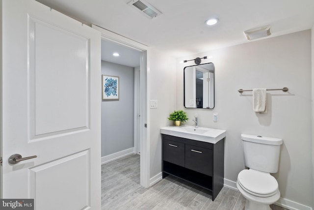 bathroom with hardwood / wood-style flooring, vanity, and toilet