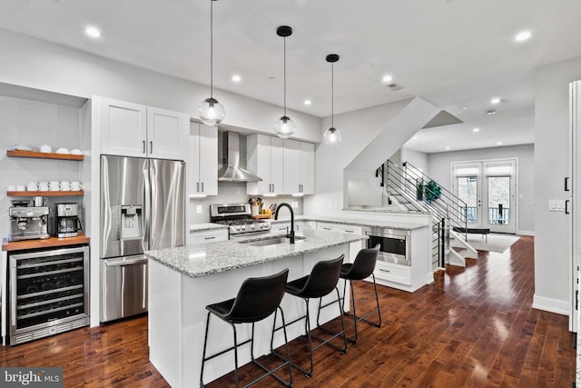 kitchen with dark hardwood / wood-style flooring, light stone counters, stainless steel appliances, beverage cooler, and wall chimney range hood