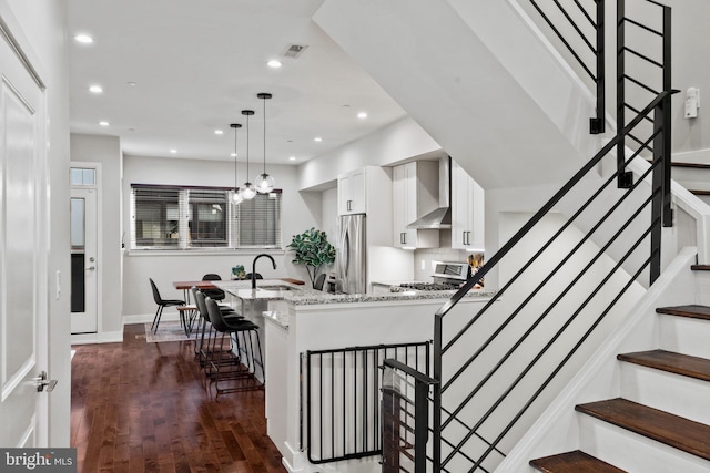 staircase with sink, a notable chandelier, and hardwood / wood-style flooring