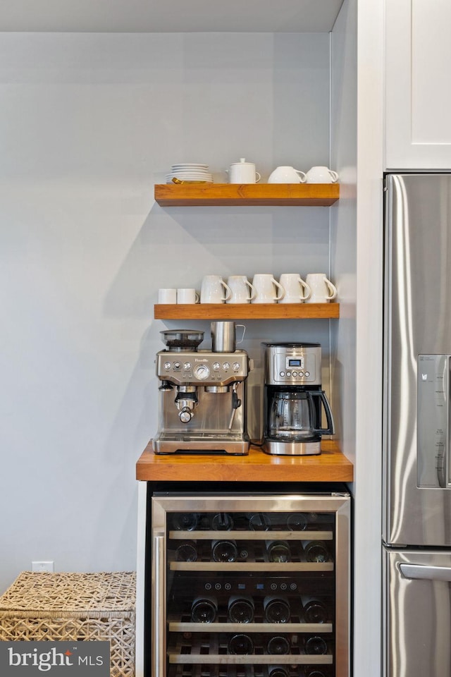 bar with wine cooler, stainless steel fridge with ice dispenser, and white cabinets