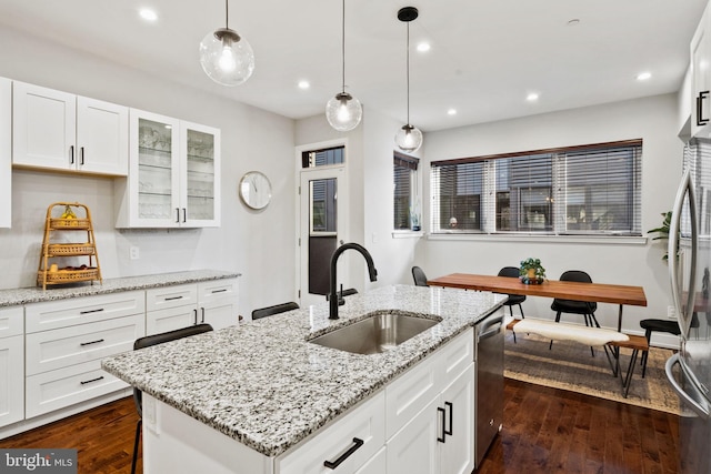 kitchen featuring white cabinetry, a center island with sink, and sink