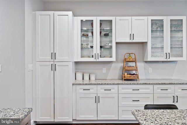 bar featuring white cabinetry and light stone counters