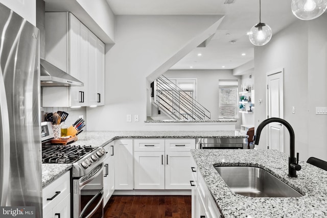 kitchen with dark wood-type flooring, sink, hanging light fixtures, white cabinetry, and stainless steel appliances