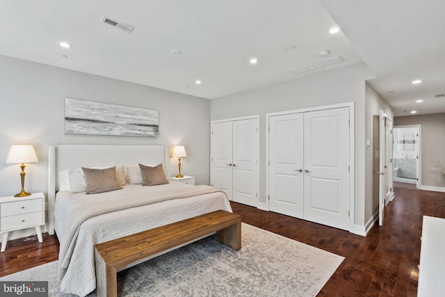 bedroom with dark hardwood / wood-style flooring and two closets