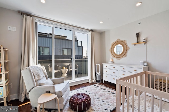 bedroom with a crib and dark wood-type flooring