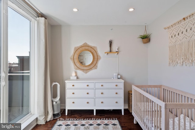 bedroom with dark wood-type flooring and a nursery area