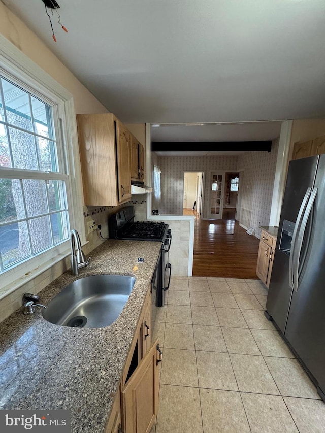 kitchen with sink, stainless steel appliances, dark stone counters, and light hardwood / wood-style flooring