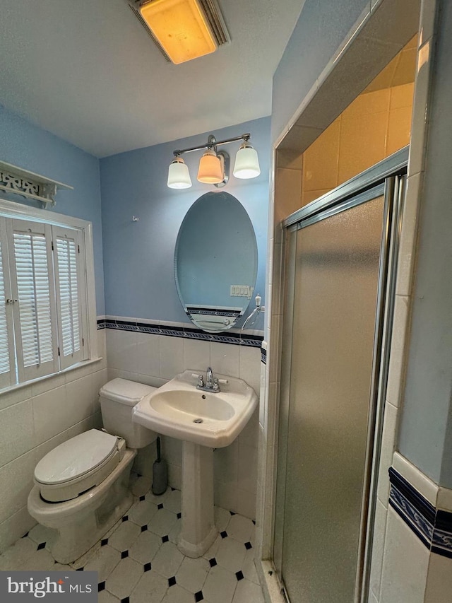 bathroom with toilet, an enclosed shower, and tile walls