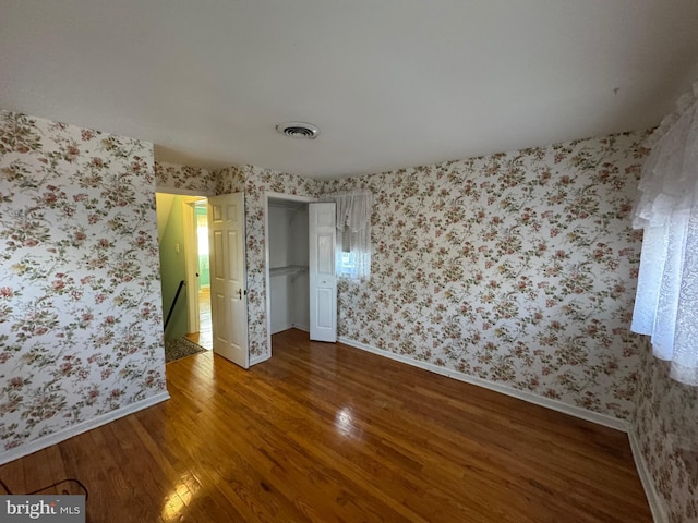 unfurnished bedroom featuring hardwood / wood-style floors, a spacious closet, and a closet