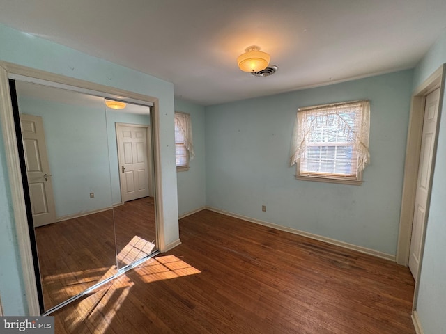 unfurnished bedroom with dark wood-type flooring and a closet