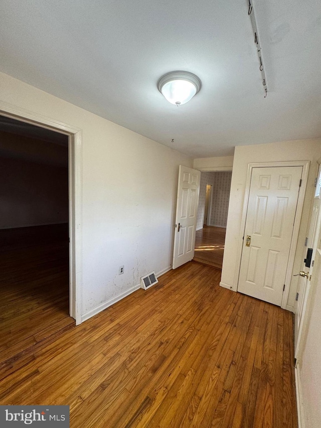 unfurnished bedroom featuring wood-type flooring and rail lighting