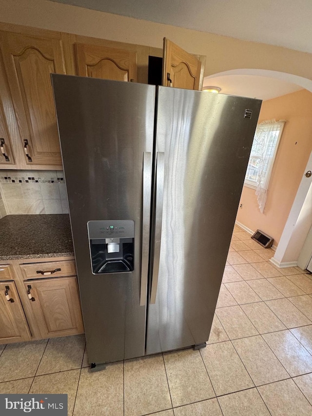 kitchen with stainless steel refrigerator with ice dispenser, light brown cabinets, and light tile patterned floors