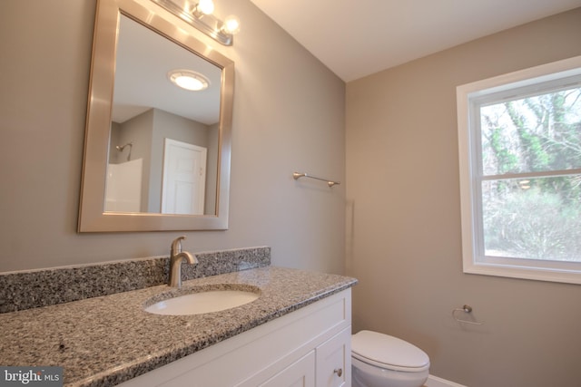 bathroom with walk in shower, vanity, and toilet