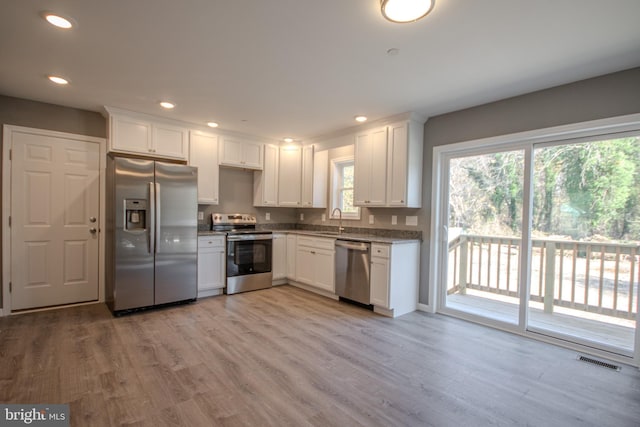 kitchen with white cabinetry, light wood-type flooring, and appliances with stainless steel finishes