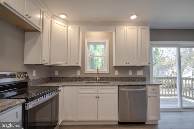 kitchen with dark stone counters, white cabinetry, sink, and stainless steel appliances