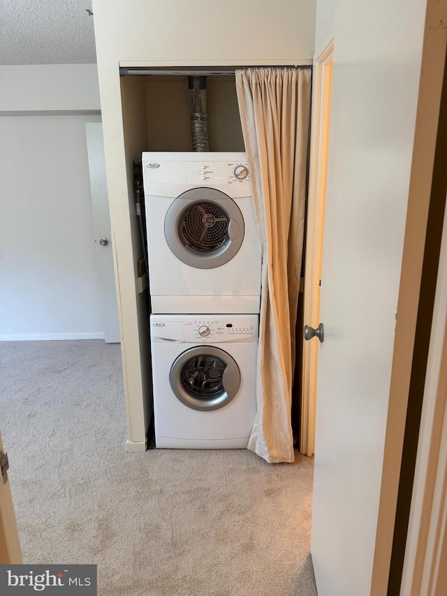 laundry area featuring light carpet, a textured ceiling, and stacked washing maching and dryer