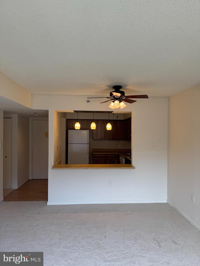 unfurnished living room with light carpet, ceiling fan, and a textured ceiling