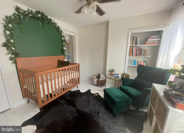 bedroom featuring ceiling fan and a nursery area