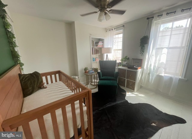 bedroom featuring ceiling fan and a crib