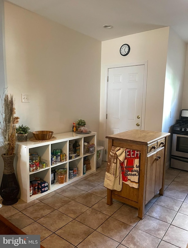 kitchen with stainless steel gas stove, light tile patterned floors, and a center island