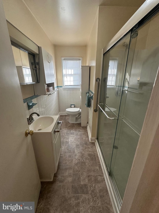 bathroom featuring toilet, an enclosed shower, tile walls, and vanity