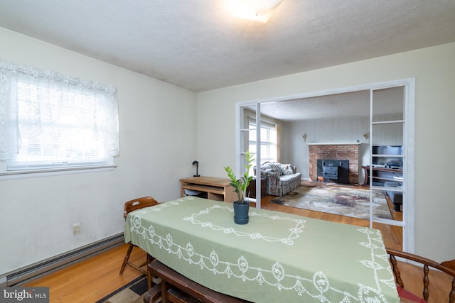 dining room with wood-type flooring, a textured ceiling, and a baseboard heating unit