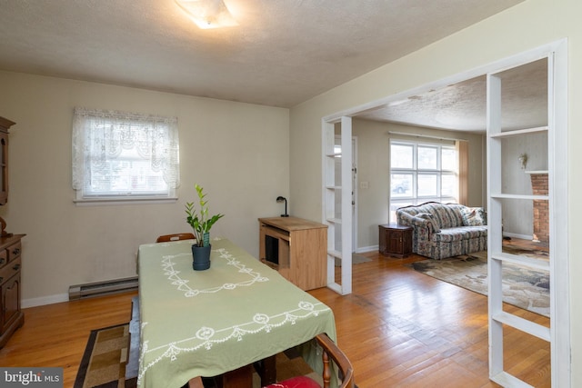 dining space featuring hardwood / wood-style floors, a textured ceiling, and baseboard heating