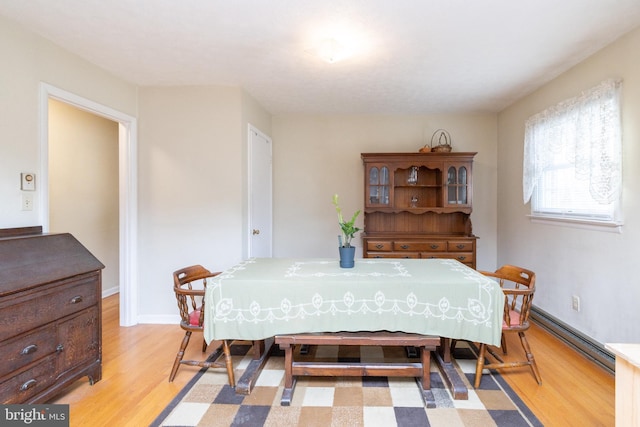 dining space featuring a baseboard radiator and light hardwood / wood-style flooring