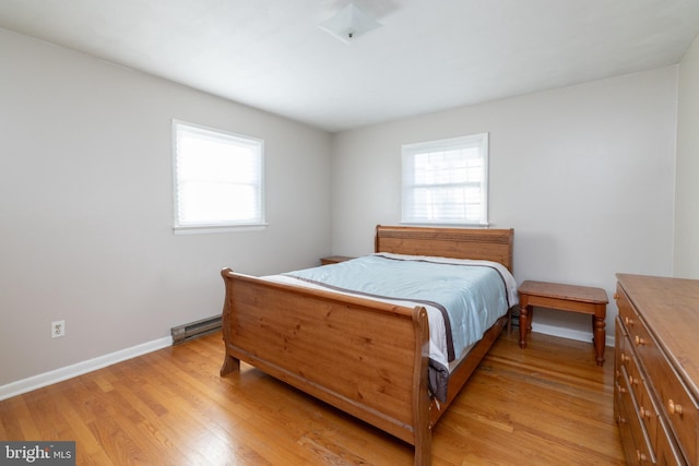 bedroom featuring light wood-type flooring and a baseboard heating unit