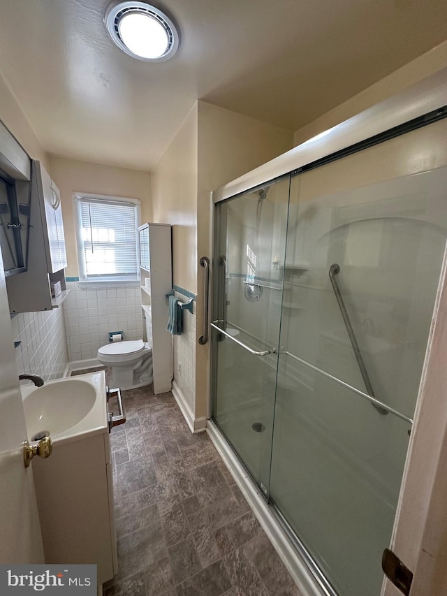 bathroom with toilet, vanity, tile walls, and walk in shower