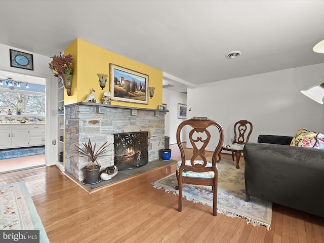 living room featuring a fireplace, wood finished floors, and visible vents