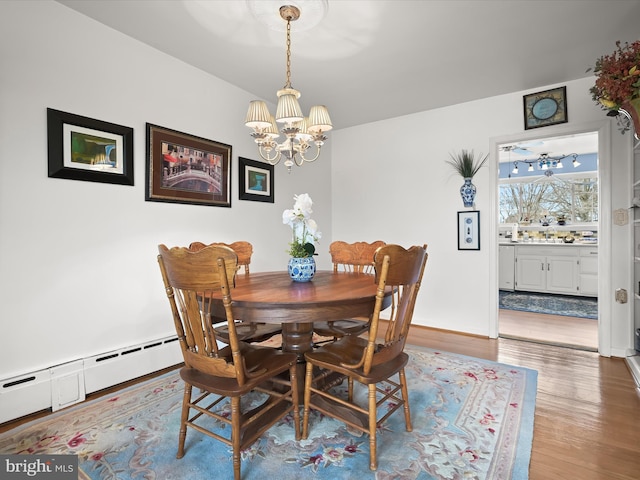 dining room featuring an inviting chandelier, baseboards, baseboard heating, and wood finished floors