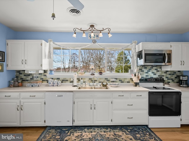 kitchen featuring dishwasher, stainless steel microwave, black electric range oven, white cabinetry, and a sink