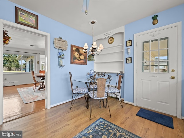 dining space with a baseboard radiator, built in shelves, baseboards, and wood finished floors