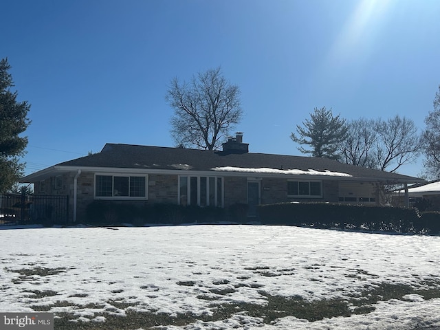 snow covered front of house featuring a chimney