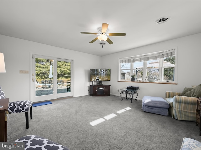 living area featuring carpet floors, a wealth of natural light, visible vents, and a ceiling fan