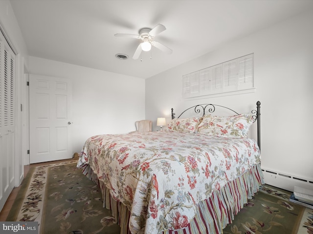 bedroom featuring a closet, baseboard heating, visible vents, and a ceiling fan