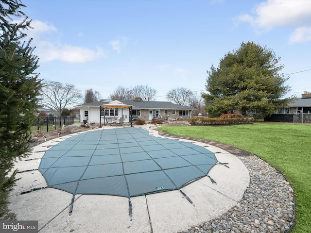 view of swimming pool with fence and a yard