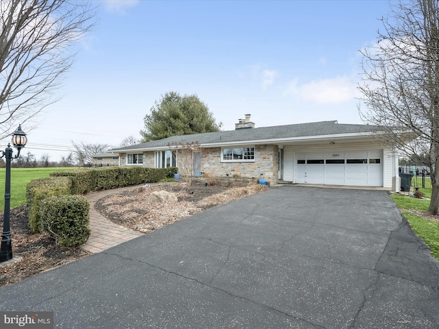 view of front of home featuring a garage, stone siding, driveway, and a chimney