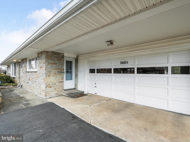 exterior space with a garage, stone siding, and driveway