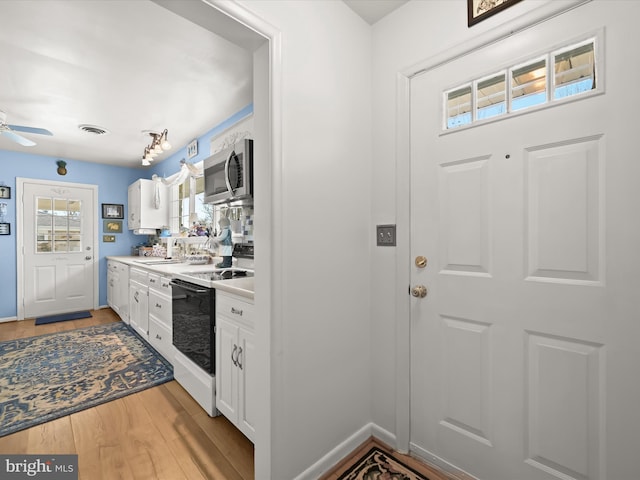 kitchen featuring visible vents, stainless steel microwave, light wood-style floors, white cabinetry, and range with electric stovetop