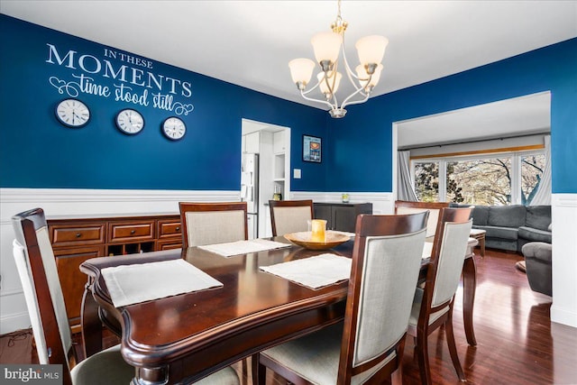 dining area with dark hardwood / wood-style floors and an inviting chandelier