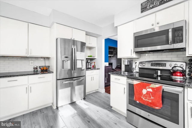 kitchen with decorative backsplash, appliances with stainless steel finishes, white cabinetry, and dark stone countertops