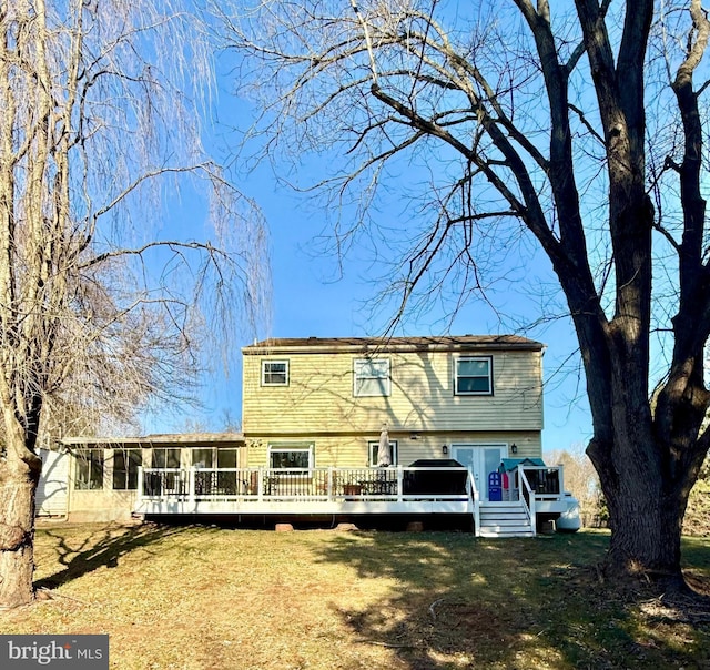 back of property with a wooden deck, a sunroom, and a yard