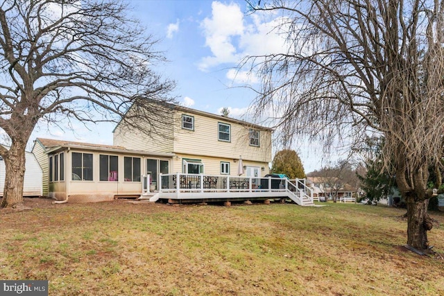 back of house featuring a deck, a lawn, and a sunroom