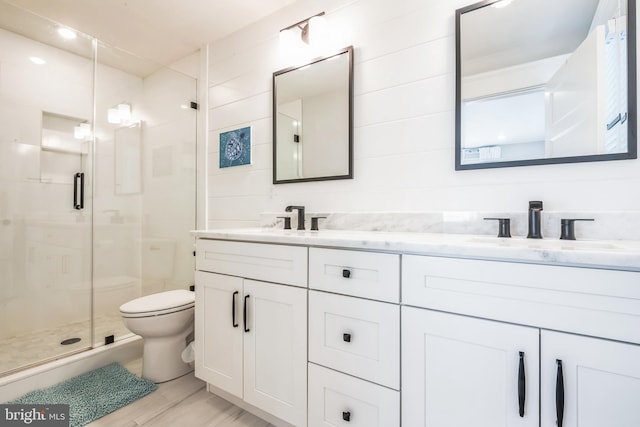 bathroom with hardwood / wood-style flooring, vanity, a shower with shower door, and toilet