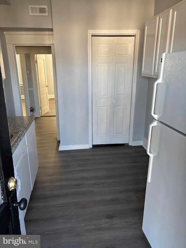 kitchen with dark hardwood / wood-style floors, white refrigerator, white cabinetry, and stone counters