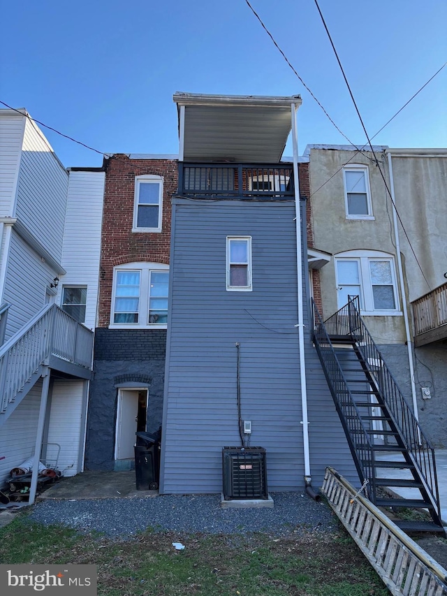 rear view of property featuring a balcony and central air condition unit