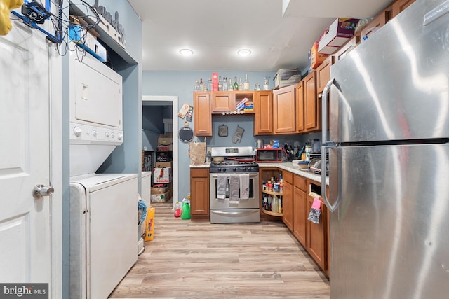 kitchen featuring stacked washer and dryer, appliances with stainless steel finishes, and light hardwood / wood-style flooring