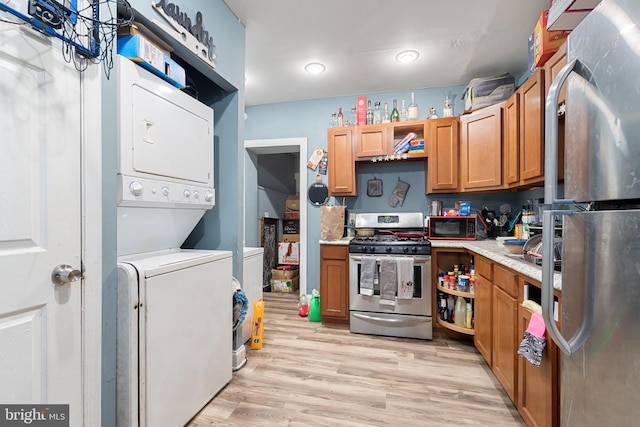 kitchen with stacked washing maching and dryer, stainless steel appliances, and light wood-type flooring